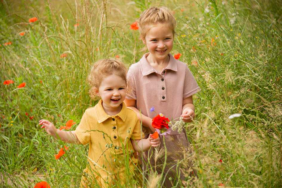 Zusjes die samen bloemen plukken tijdens familiefotografie