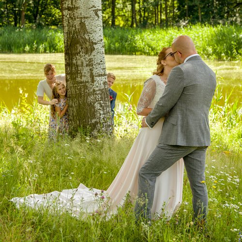 Tijdens het maken van de trouwfoto's worden spontane kussen vast gelegd